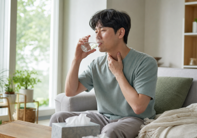 여름철 집에서 물을 마시며 목의 불편을 관리하는 모습