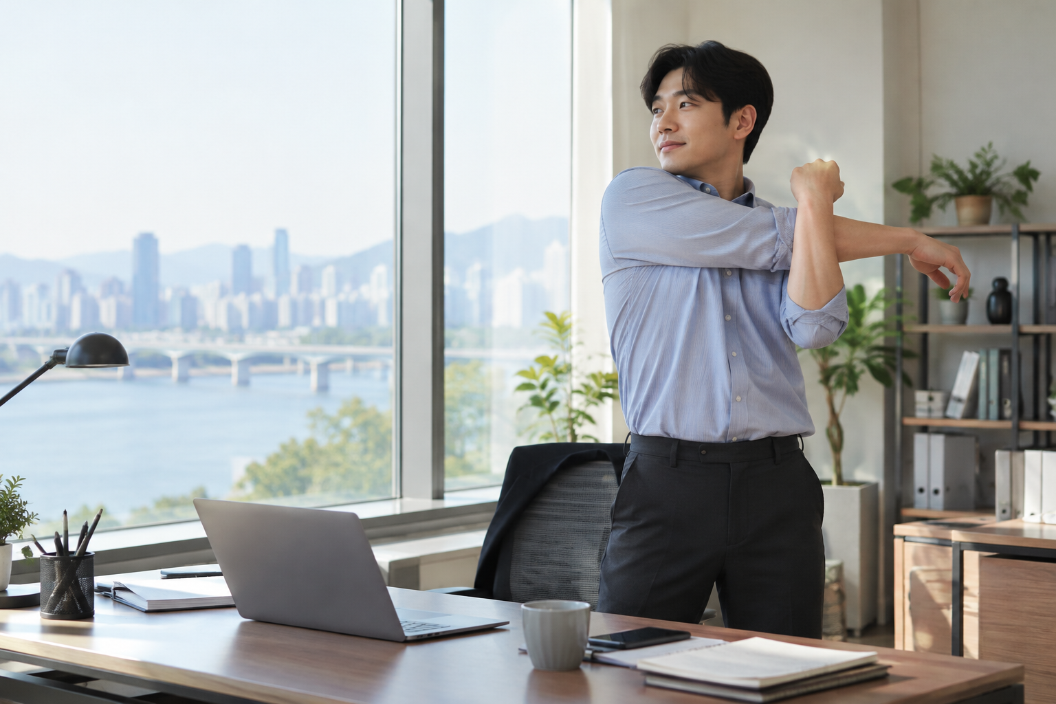 사무실 책상 옆에 서서 어깨를 스트레칭하는 남성